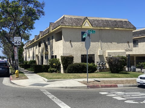 A street view with a building, a car and a stop sign.