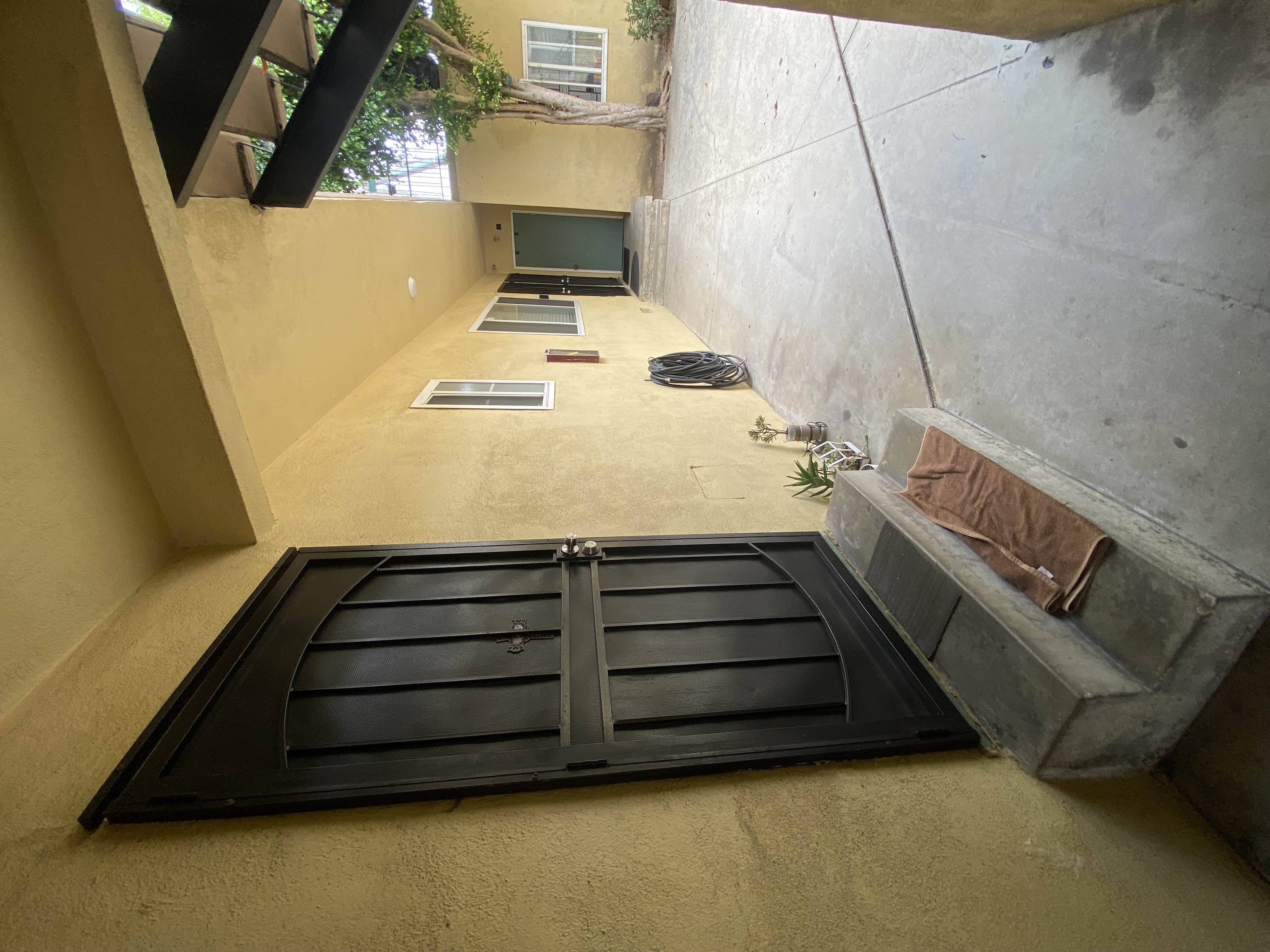 A black door with a metal handle is in the center of a concrete wall.
