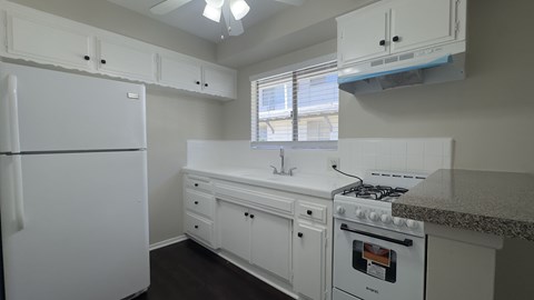 A white kitchen with a fridge, stove, and sink.