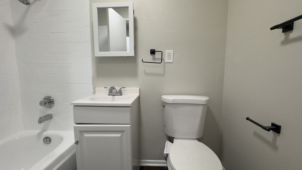 A white toilet sits next to a white sink in a small bathroom.