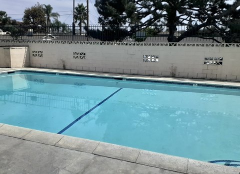 A rectangular pool with a blue tiled edge and a white fence around it.