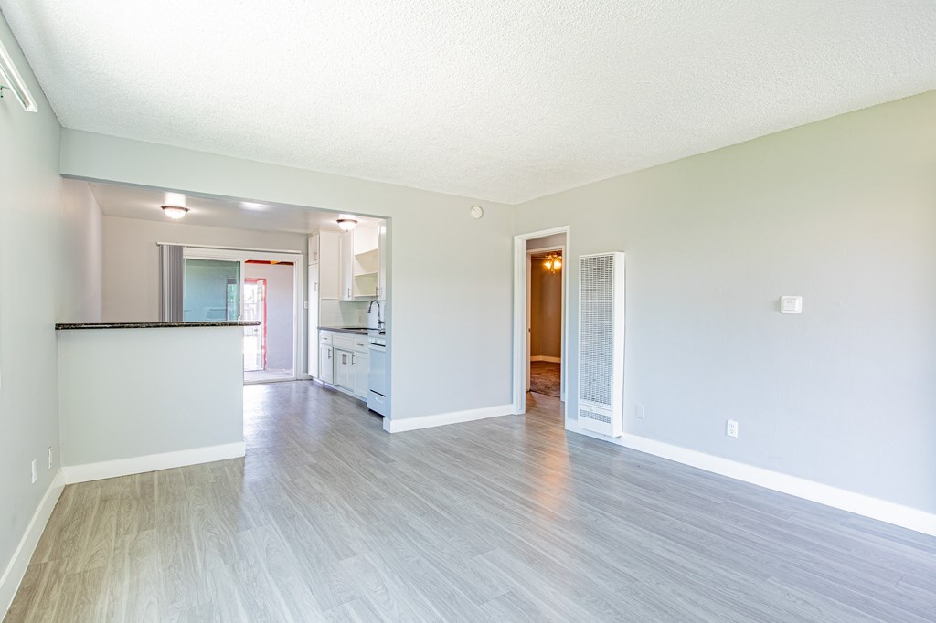 A spacious living room with a kitchen in the background.