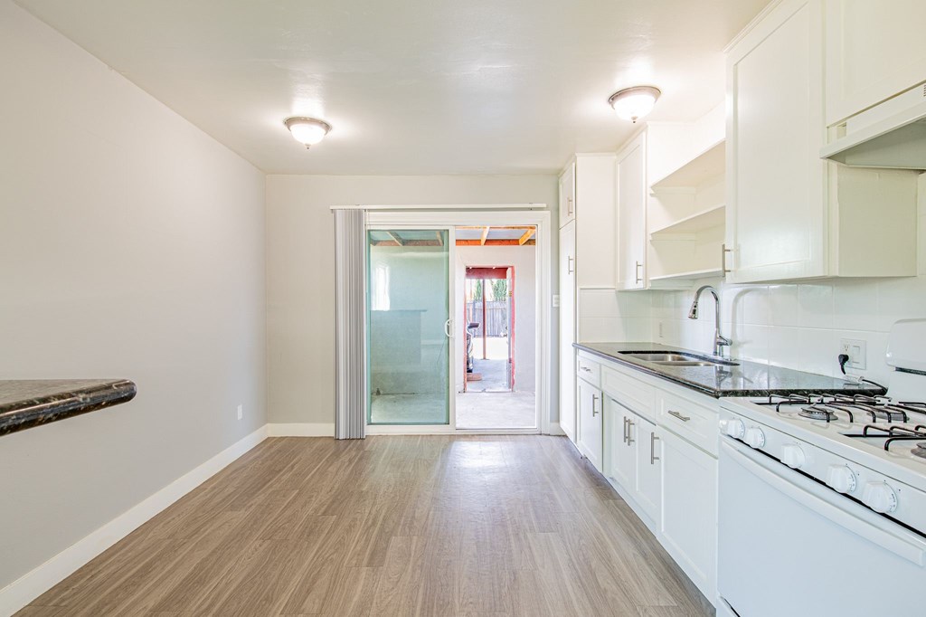 A kitchen with white cabinets and a wooden floor.