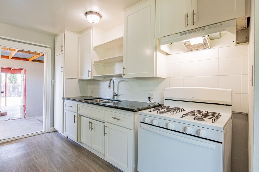 A white kitchen with a stove and cabinets.