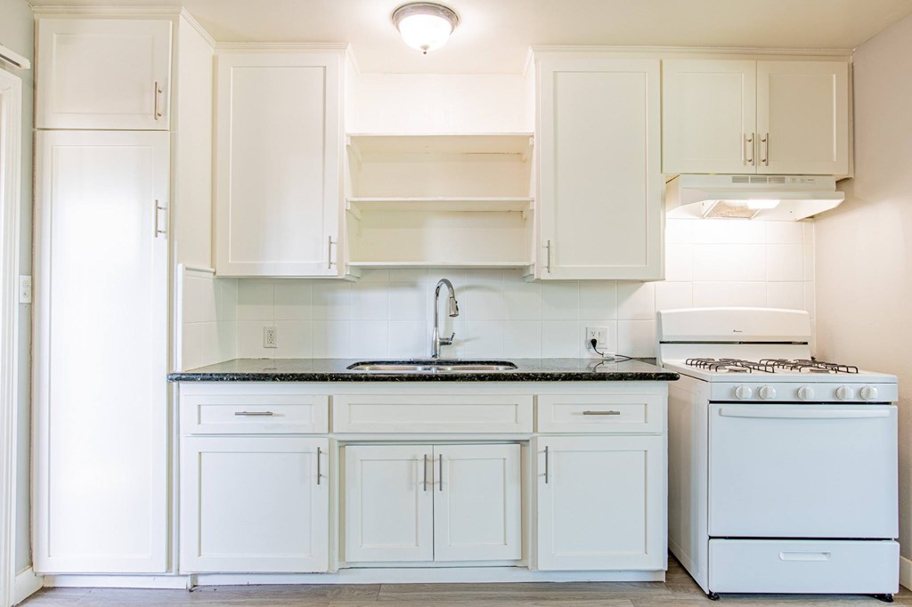 A kitchen with white cabinets and appliances.