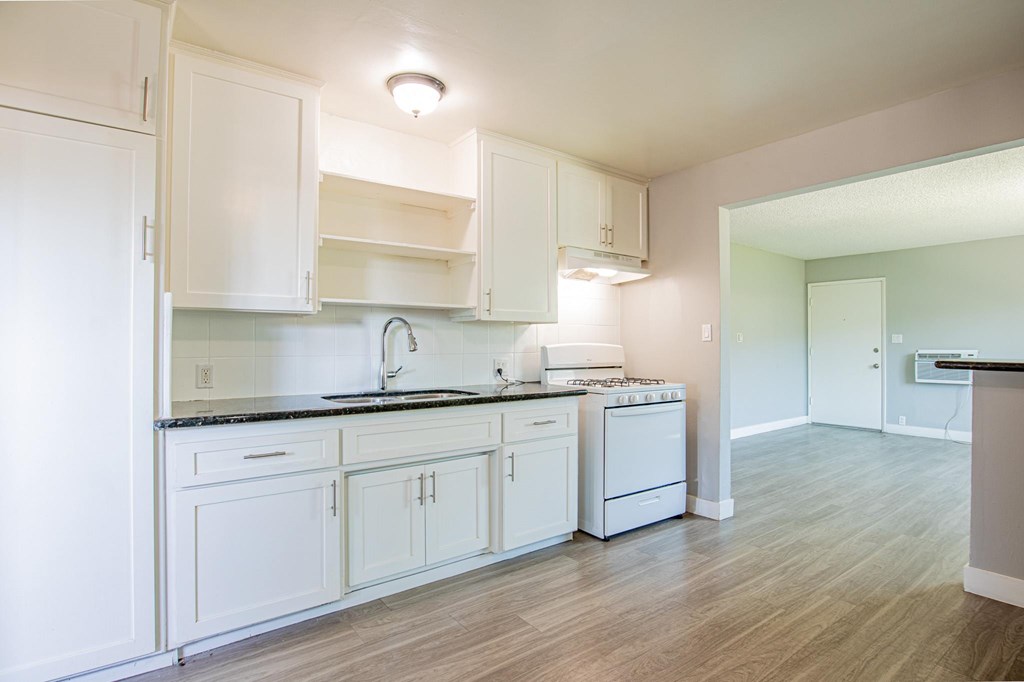 A kitchen with white cabinets and a black countertop.