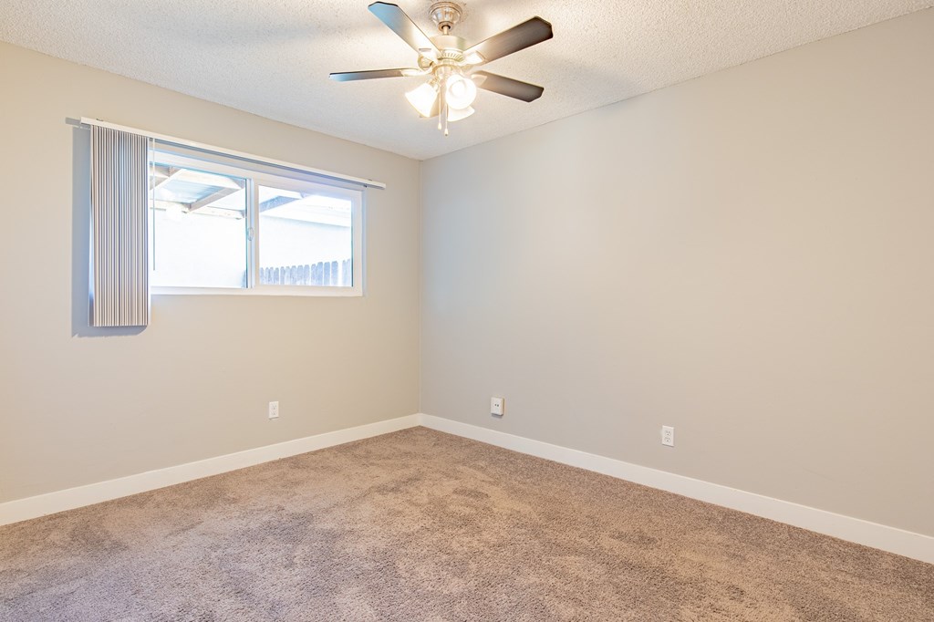 A room with a ceiling fan and carpeted floor.