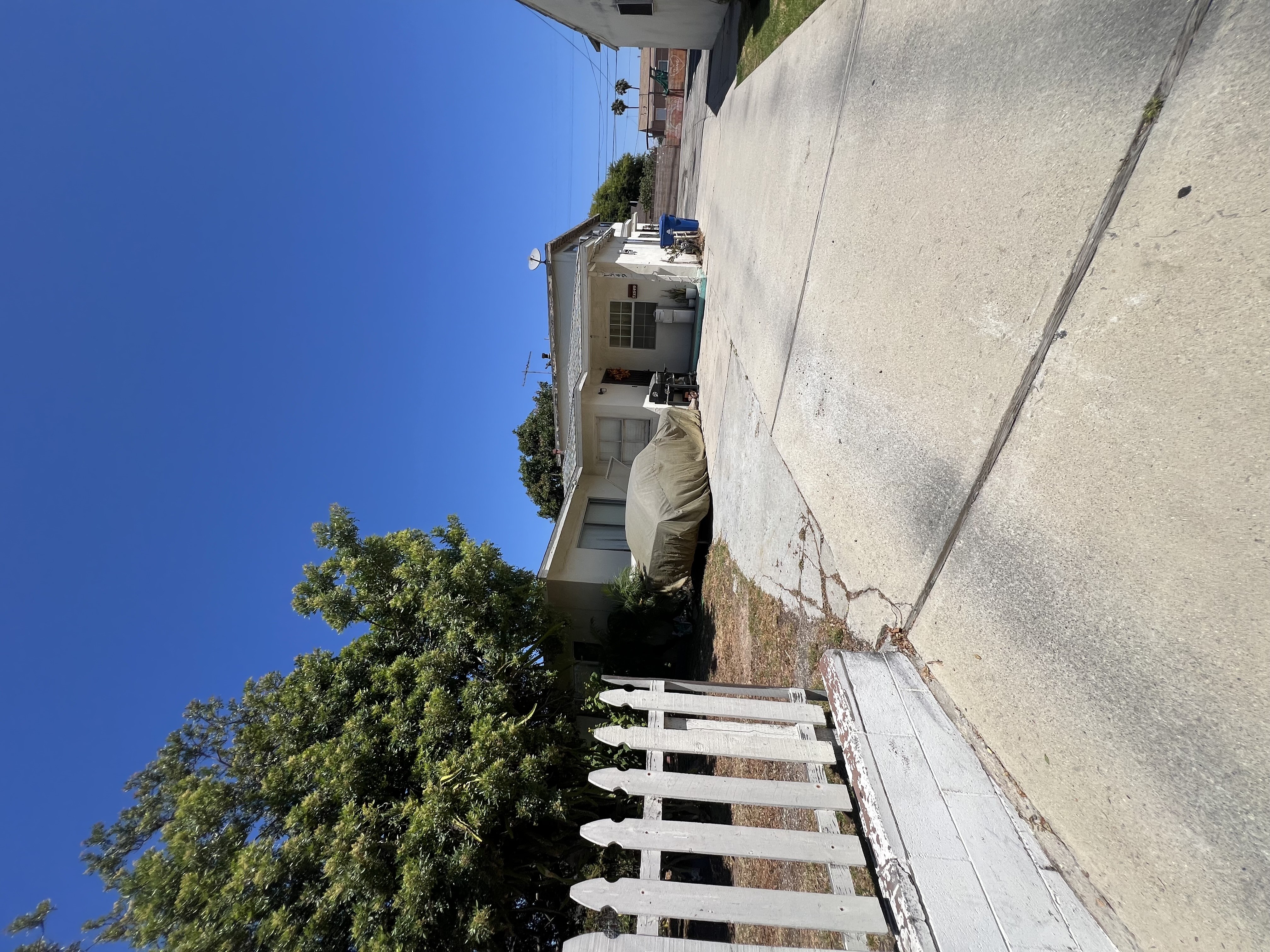 A house with a white fence and a tree in front of it.