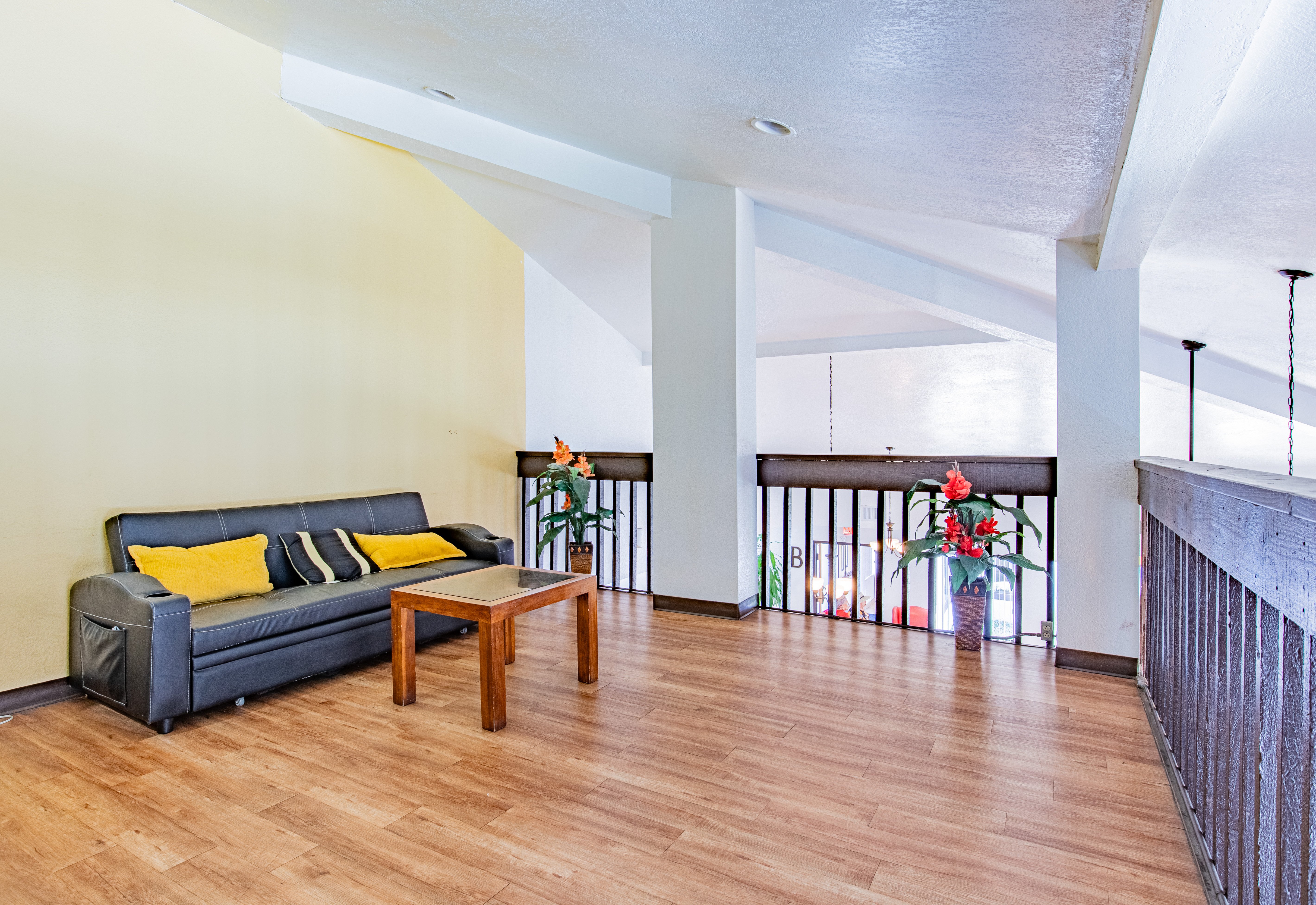 A living room with a black couch and a wooden coffee table.