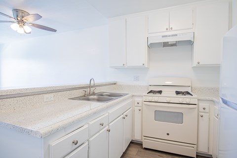 A white kitchen with a fan on the ceiling.