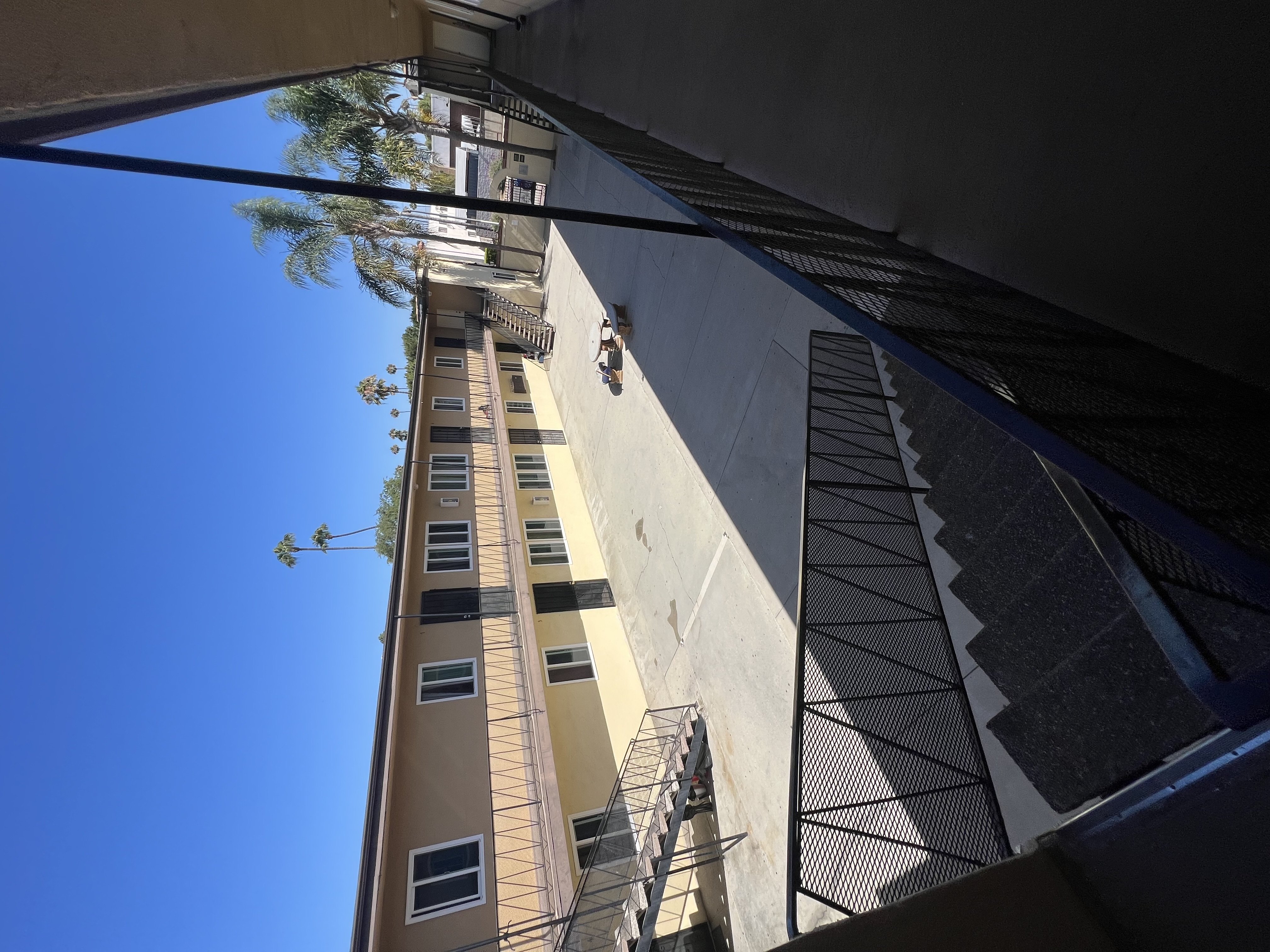 A tall building with a balcony and a tree in the background.