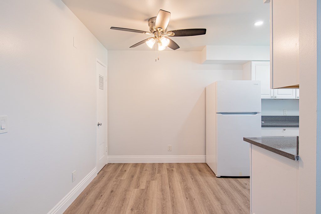 A kitchen with a white fridge and a ceiling fan.