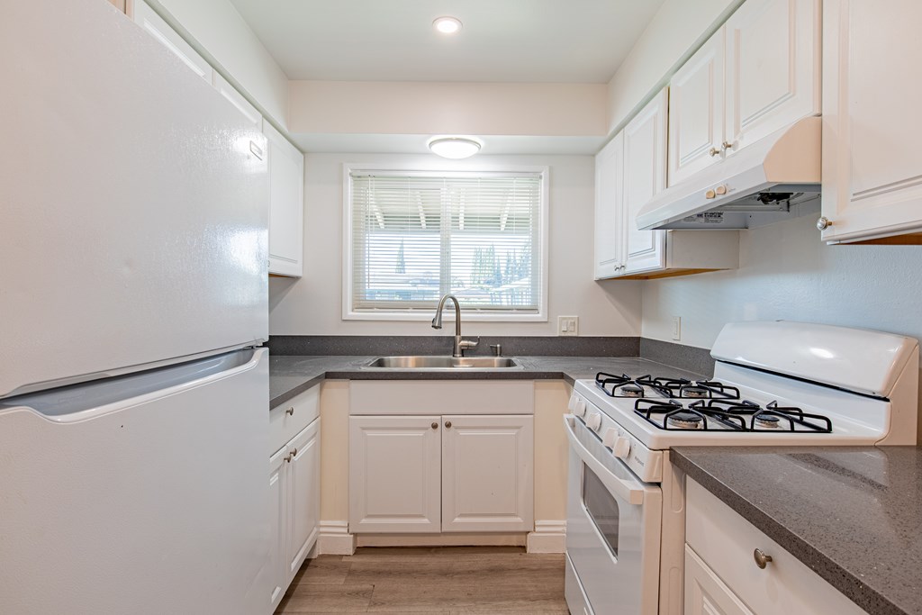 A kitchen with white appliances and cabinets.
