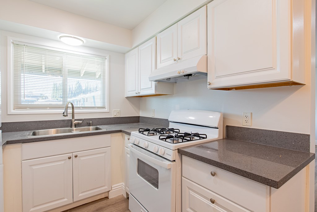A white kitchen with a stove and sink.