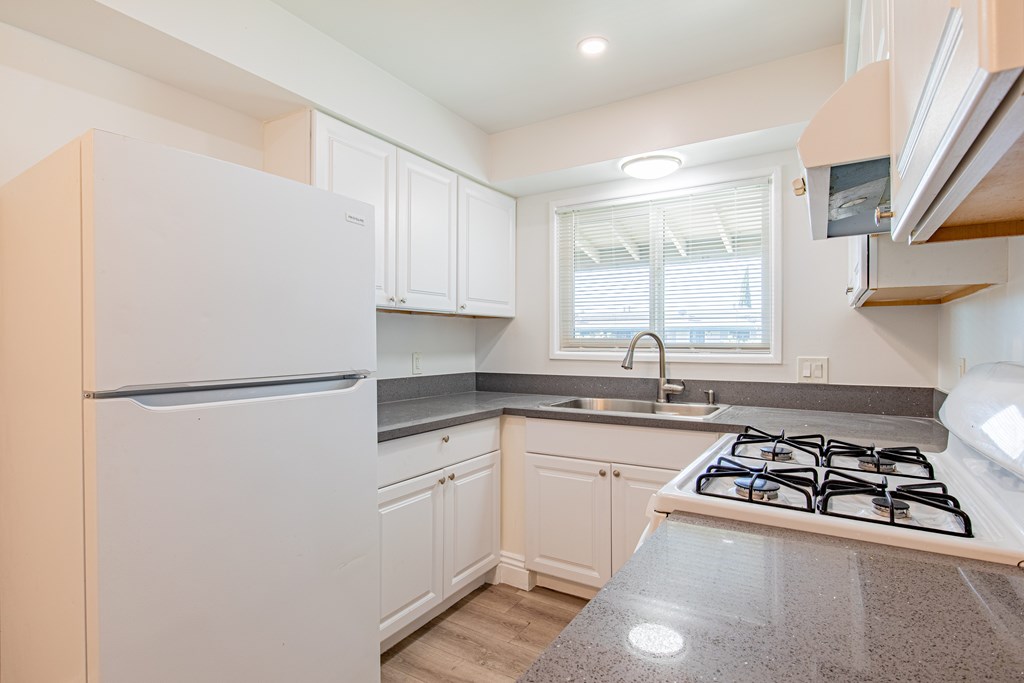 A kitchen with a white refrigerator, a white stove, and white cabinets.