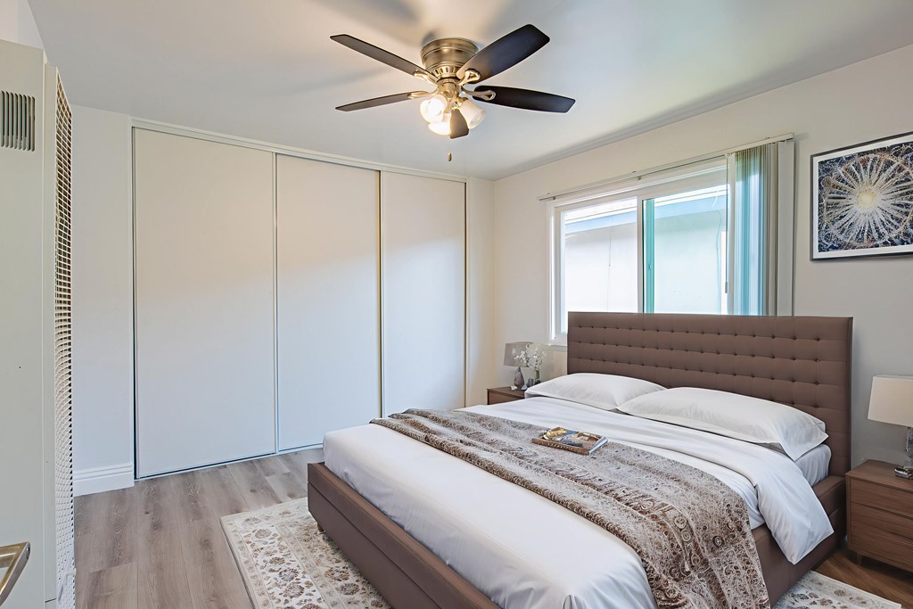 A bedroom with a large bed and a ceiling fan.