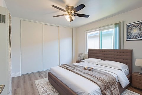 A bedroom with a large bed and a ceiling fan.