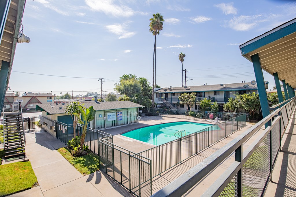 A pool surrounded by a fence and a building in the background.