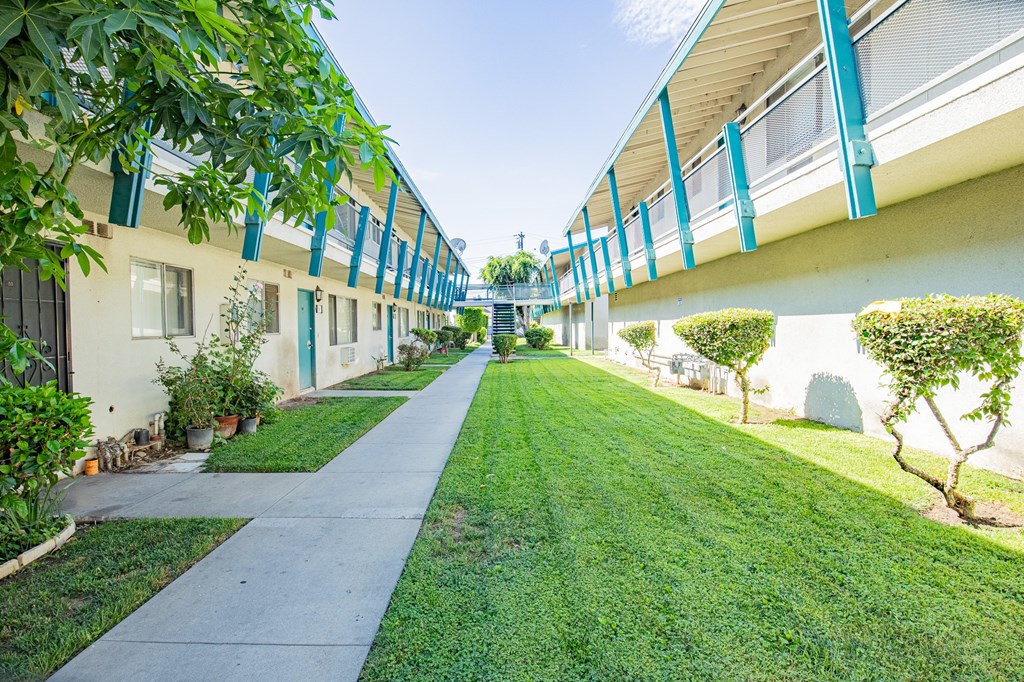A long, narrow walkway between two buildings with greenery on the sides.