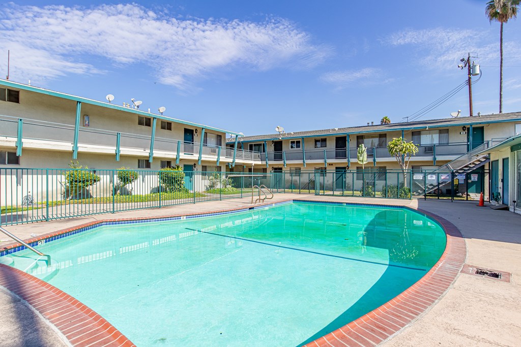 A swimming pool in front of a building with a clear blue sky.