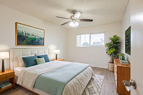 A bedroom with a bed, nightstand, and a painting on the wall.