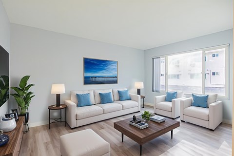 A living room with a large painting on the wall and two white couches.