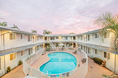 A swimming pool is surrounded by a fence and is in front of a building.