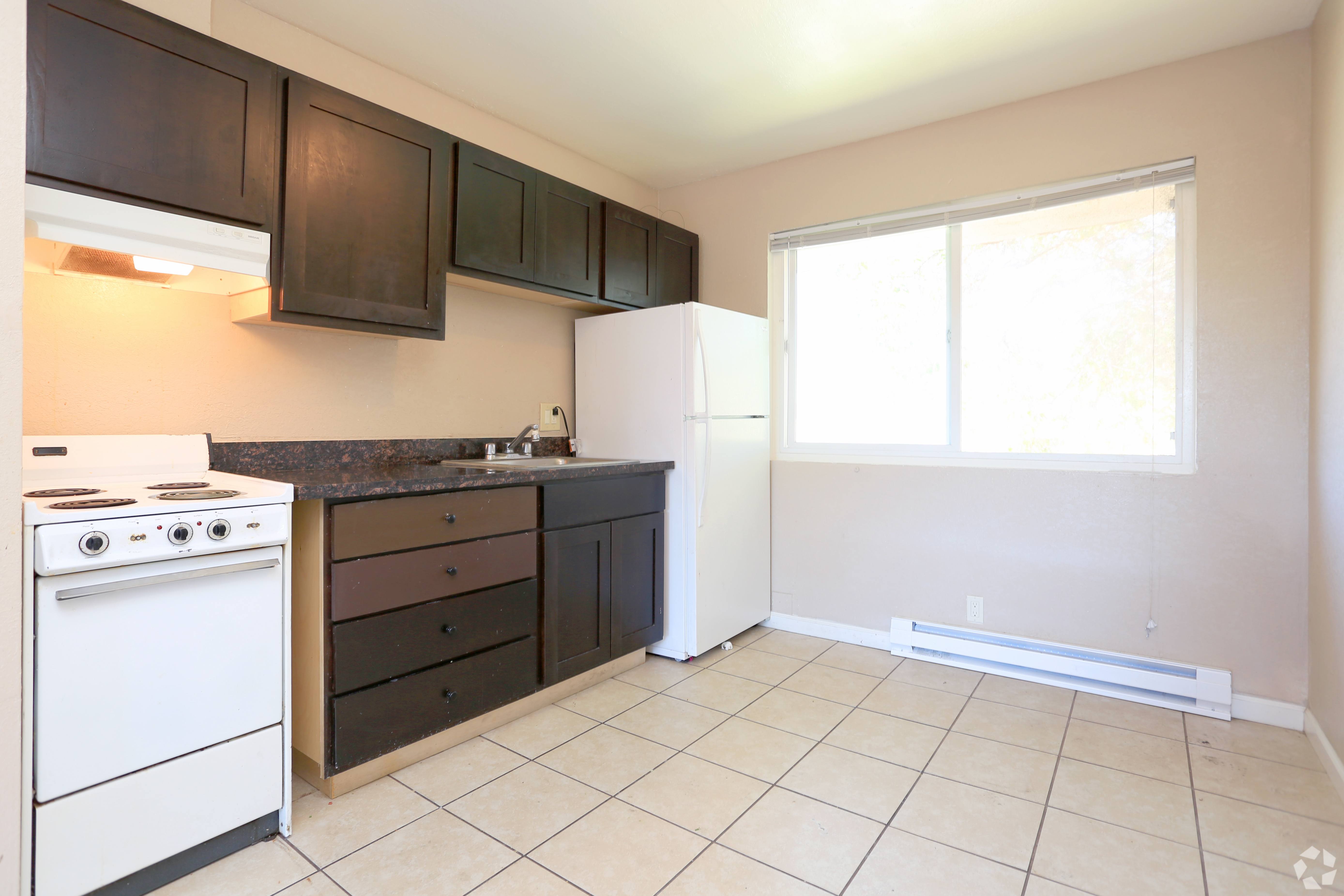 A kitchen with white appliances and brown cabinets.