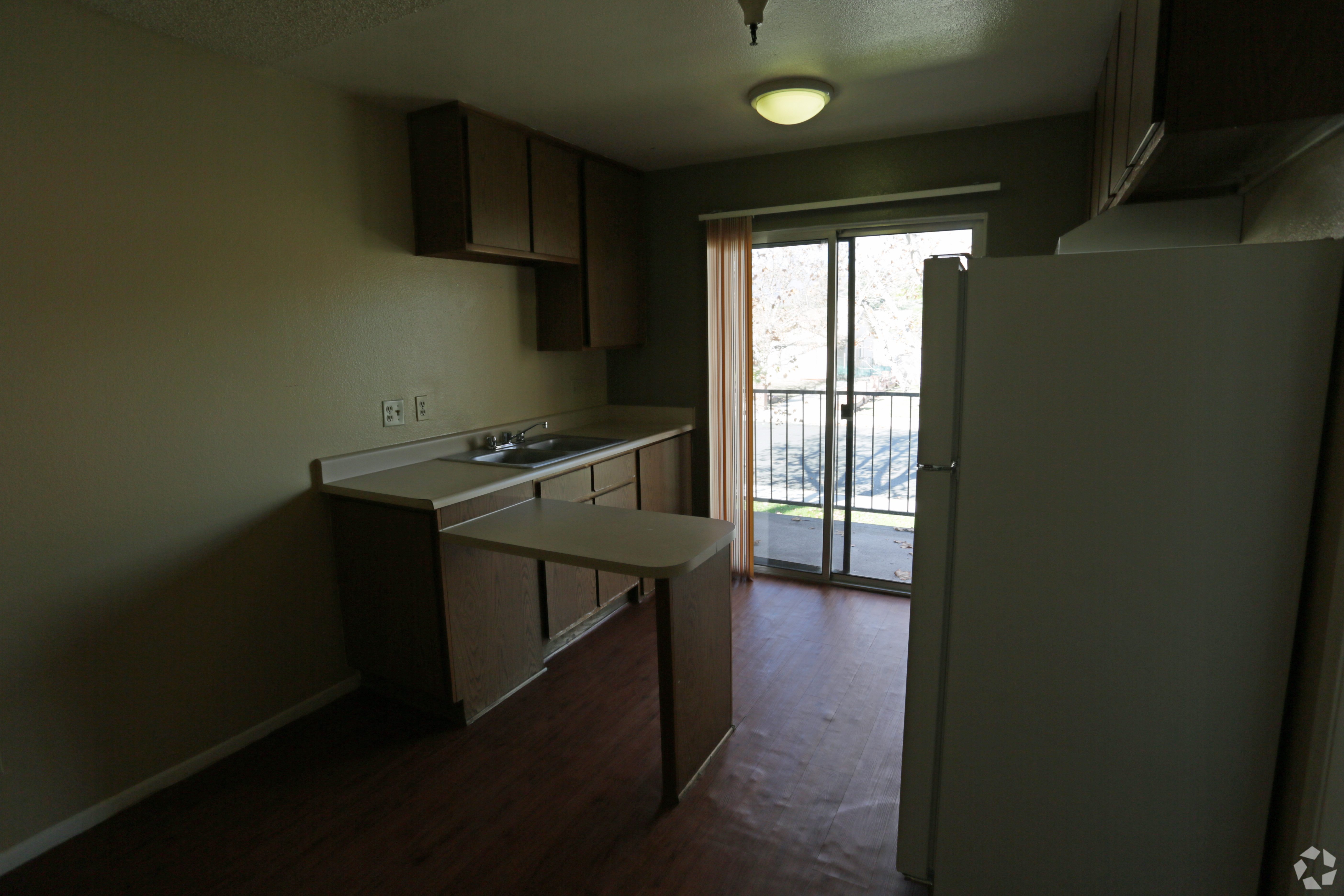 A kitchen with a refrigerator, sink, and cabinets.