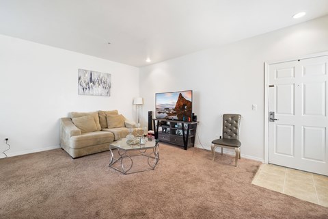 A living room with a brown carpet and a white door.
