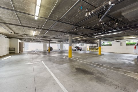 A spacious parking garage with concrete floors and yellow bollards.