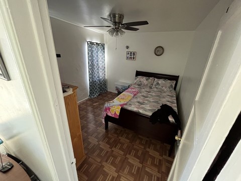 A bedroom with a bed, dresser, and ceiling fan.