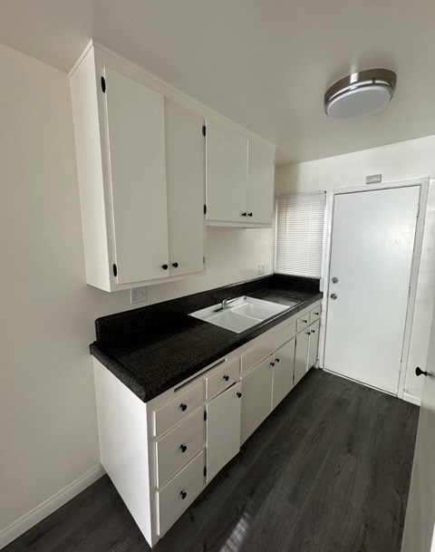 A kitchen with white cabinets and a black countertop.