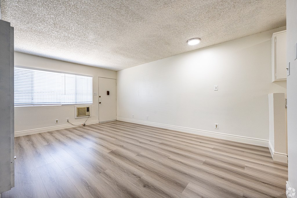 A room with wooden flooring and a window with blinds.