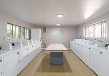 an empty kitchen with white cabinets and a table at North View Terrace, Montebello