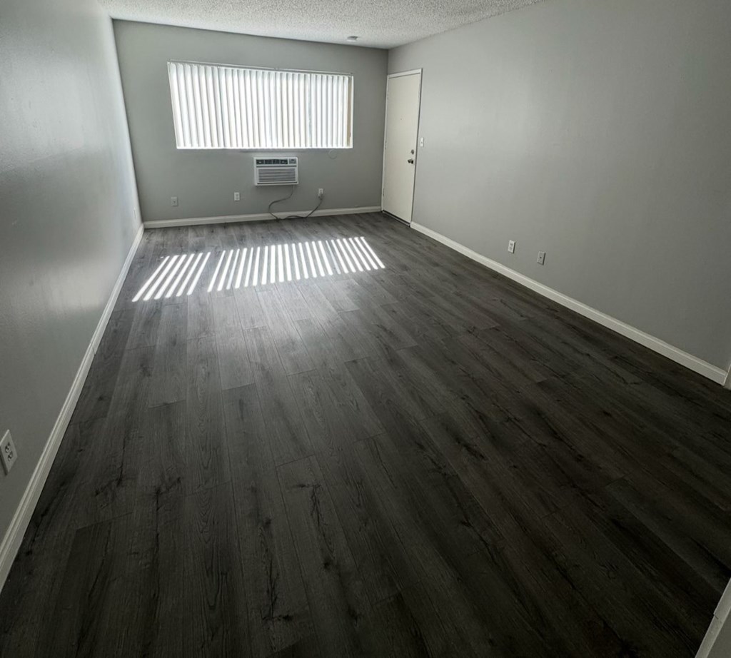 A room with wooden flooring and a window with blinds.