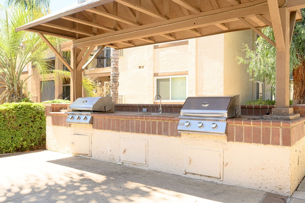an outdoor kitchen with two grills and a sink at Oak Terrace Senior Apts, Hemet, CA