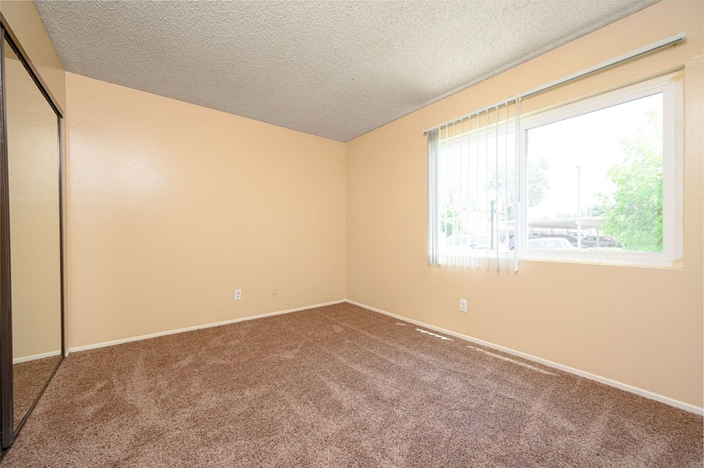 a bedroom with a large window and a carpeted floor at Oak Terrace Senior Apts, California