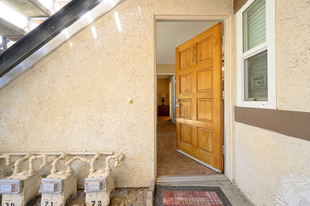 an open door leading to a hallway with a wooden door and white boxes in front of it at Oak Terrace Senior Apts, Hemet California