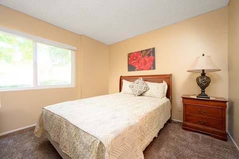 a bedroom with a bed and a nightstand at Oak Terrace Senior Apts, Hemet, 92543