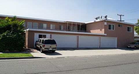 A tan house with a car parked in front.