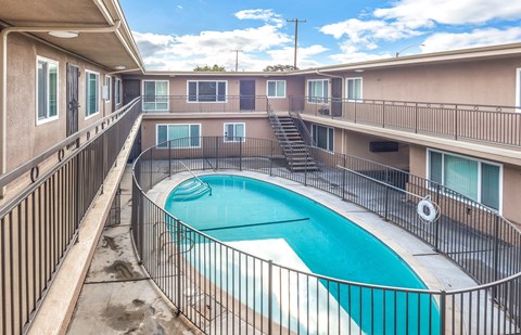 A small pool in a courtyard surrounded by a metal fence.