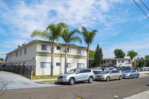 A row of houses with cars parked in front.