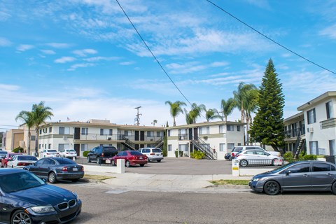 A parking lot with cars and apartment buildings in the background.
