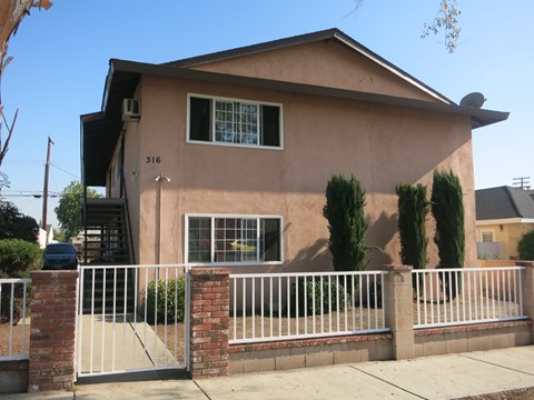 A house with a white fence and a brick pillar.