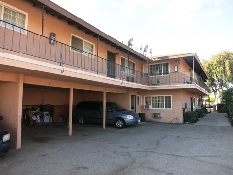 A carport with a black car and a blue car parked in it.