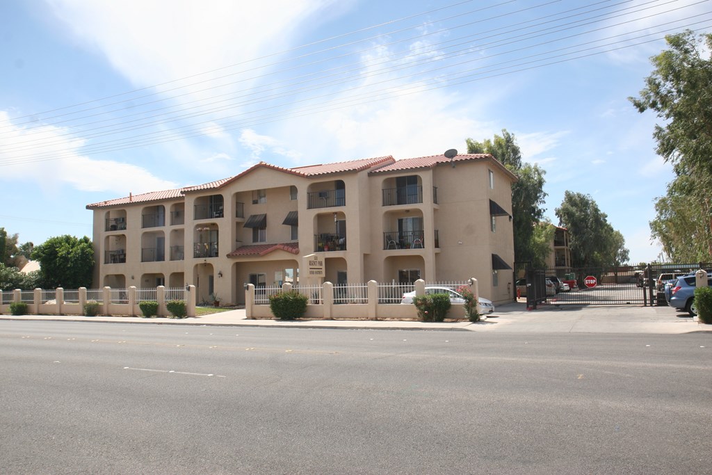 A large apartment building with a parking lot in front.