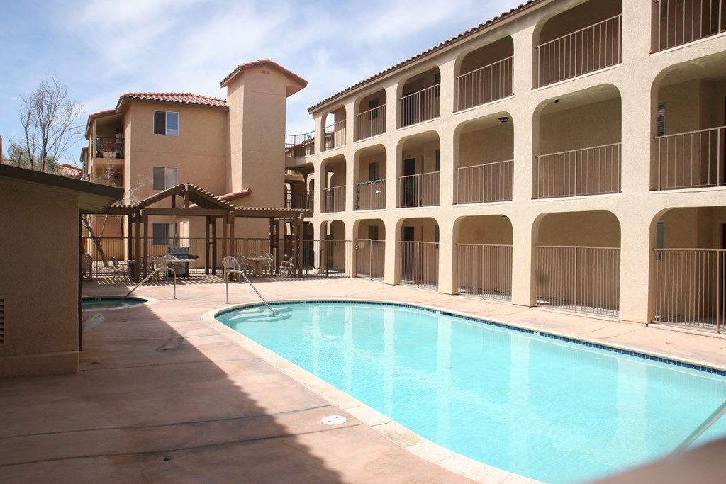 A large swimming pool in front of a building with a balcony.