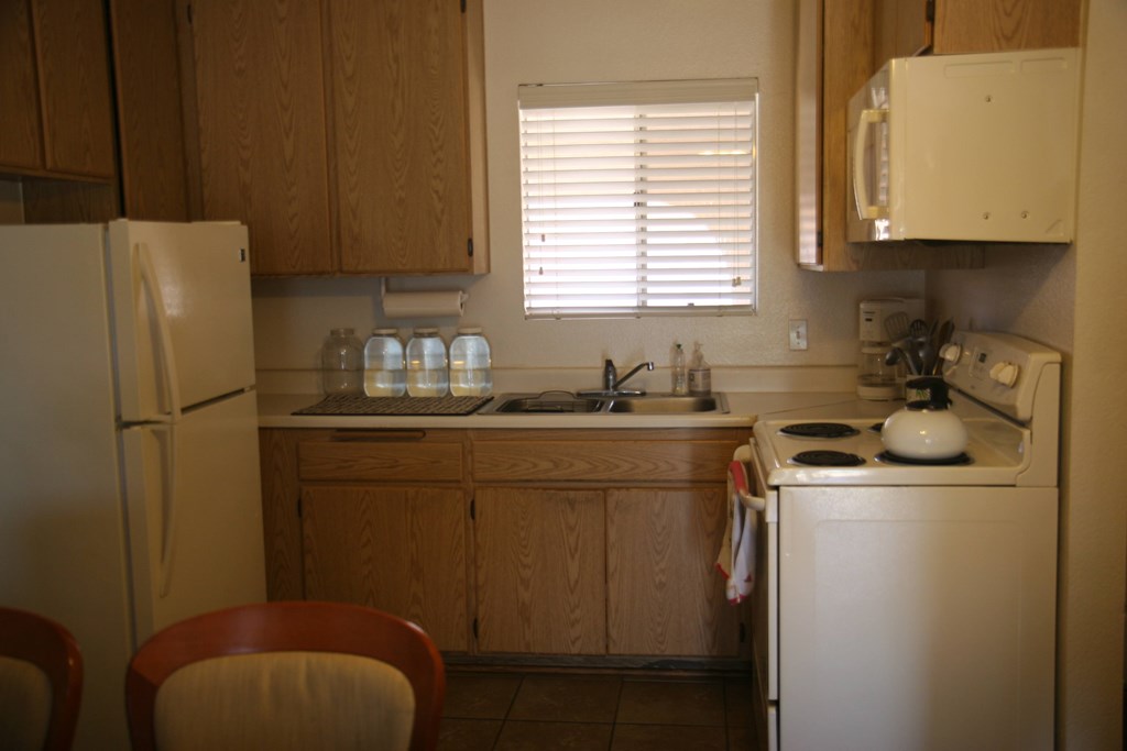 A kitchen with a refrigerator, sink, and stove.