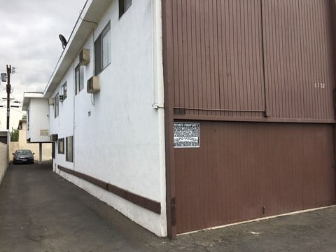 A white building with a brown door and a sign on it.